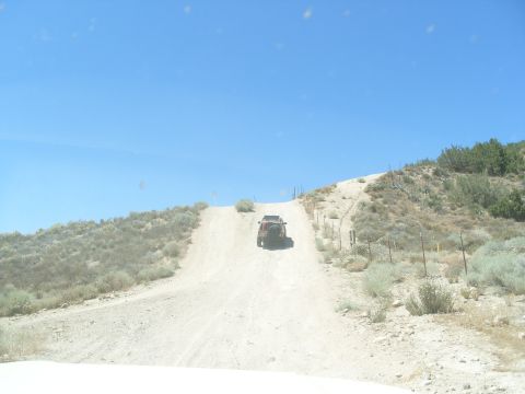1995 Ford Bronco - An off-road vehicle ascends a dusty incline on a sunny day.