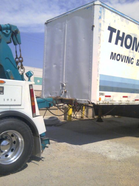 1992 Ford Bronco - A tow truck, marked with "1956", is connected to a trailer belonging to THOM MOVING &.