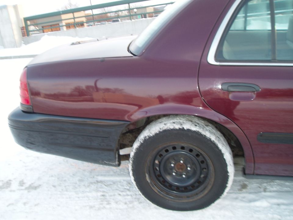 Maroon sedan rear quarter panel and wheel in snow. 1998 Ford Crown Victoria