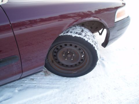 1999 Ford Crown Victoria - Front wheel and fender of a 1999 Ford Crown Victoria covered in snow.