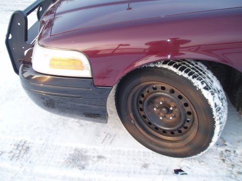1999 Ford Crown Victoria - This maroon Ford Crown Victoria is parked in the snow, showing its front corner and a push bar.