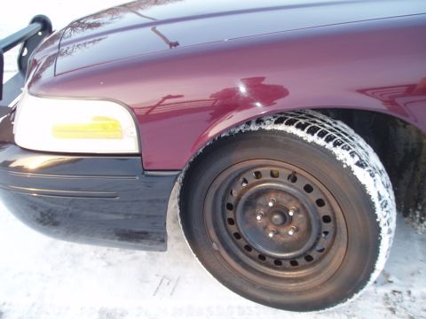 1999 Ford Crown Victoria - Close-up of a maroon Ford Crown Victoria's front fender and wheel in the snow.