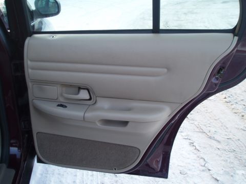 1999 Ford Crown Victoria - Interior view of a car's rear passenger door panel, showing the armrest and window controls.