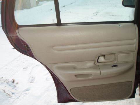 1999 Ford Crown Victoria - Interior door panel of a vehicle, showing the armrest and window controls.