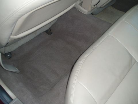 1999 Ford Crown Victoria - Interior view of a car showing tan leather seats and gray carpeting, carpeted flooring, floor mats with a visible watermark.
