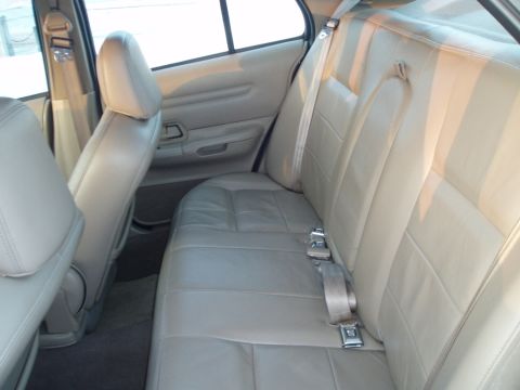 1999 Ford Crown Victoria - Interior view of the tan leather rear seats and door panel of a car.