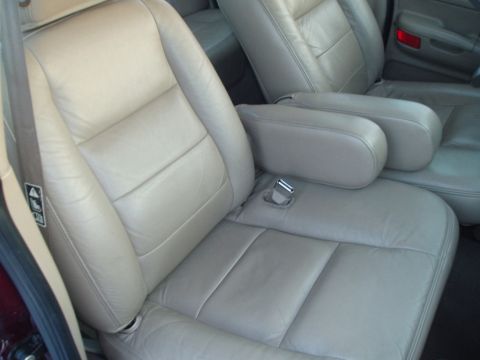 1999 Ford Crown Victoria - Interior view of a car's tan leather seats and armrests, with a red taillight in the background.