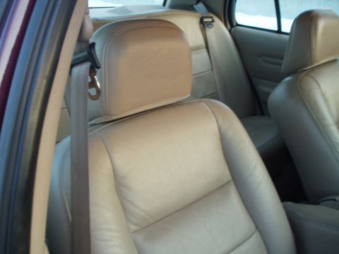 1999 Ford Crown Victoria - Interior view showing tan leather seats and a seatbelt in a vehicle.