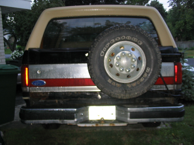 Rear of a tan and black Ford Bronco with a spare tire mounted on the back