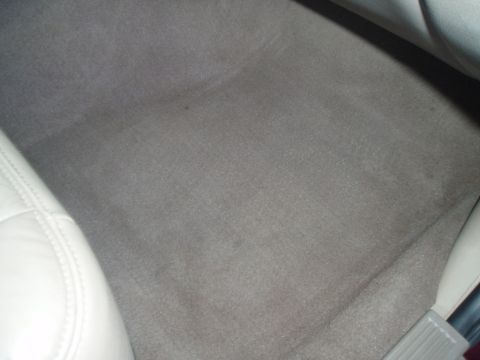 1999 Ford Crown Victoria - Close-up of the carpeted floor inside a vehicle, showing wear and some stains.