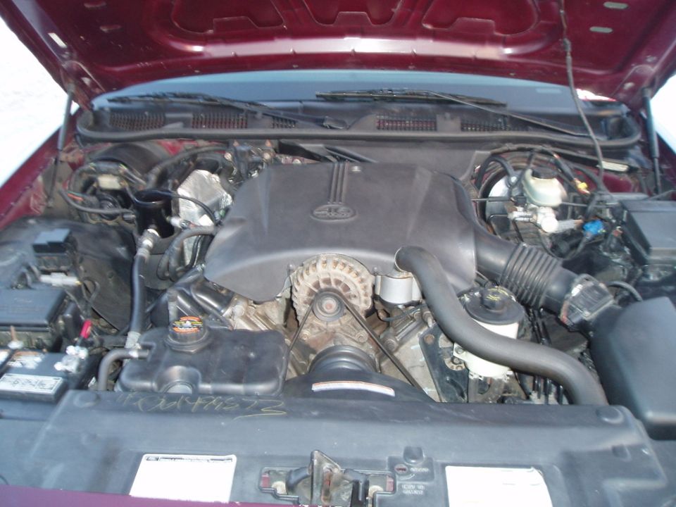 Engine bay of a maroon 1998 Ford Crown Victoria, showing the V8 engine, alternator, and battery