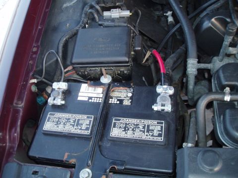 1999 Ford Crown Victoria - Close-up view of the engine bay, showing dual batteries and a Ford-branded fuse box.