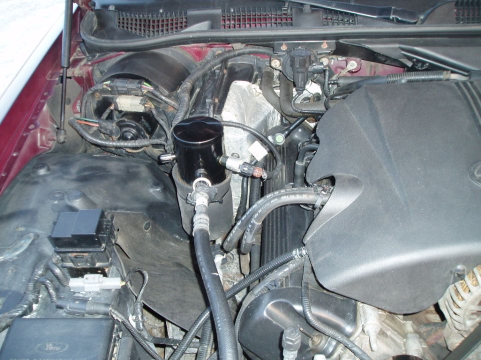Engine bay showing an oil catch can installed near the firewall, with hoses and wiring visible