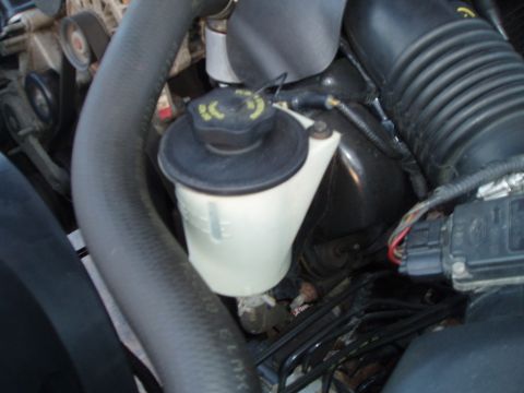 1999 Ford Crown Victoria - Engine bay detail showing a fluid reservoir with fill lines and a black cap.