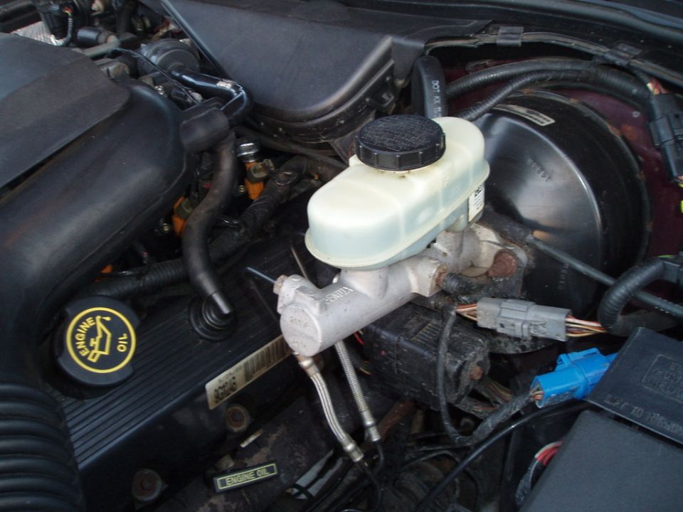 Engine bay with brake fluid reservoir and master cylinder. Yellow engine oil cap visible