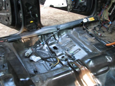 1999 Ford Crown Victoria - Overhead view into a car's stripped rear floor pan with the seats, carpet and rear seat cushion removed, exposing bare stamped sheet metal,…