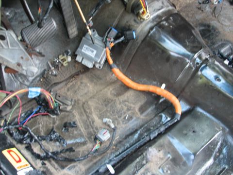 1999 Ford Crown Victoria - Stripped driver's footwell of a car under teardown, showing the ribbed brake pedal pad and dead pedal at upper left and the bare floor pan…