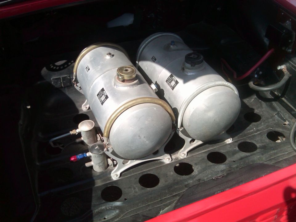 Two silver tanks with brass trim and labels in red vehicle cargo area