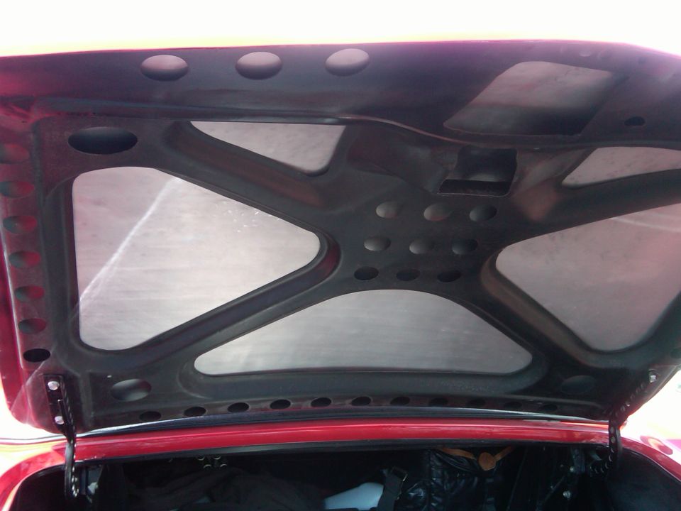 underside of a red car hood with black bracing and insulation panels