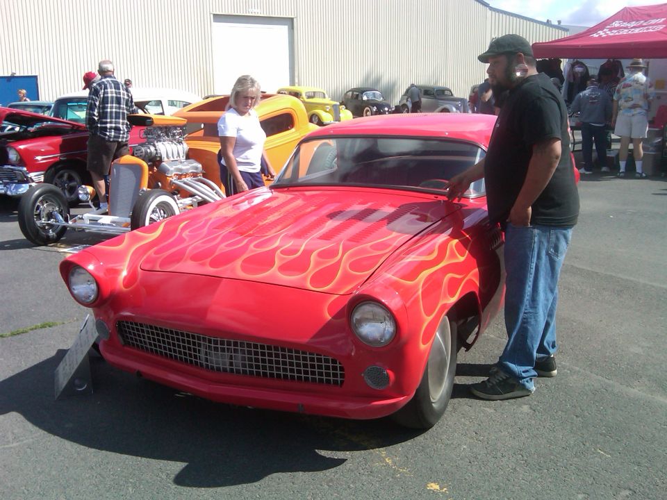Red classic car with flame decals, front view, showing grille and headlights