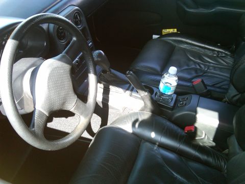 1988 Ford Bronco - The interior of a car is shown, leather seats and a center console with a gear shifter and cup holder.