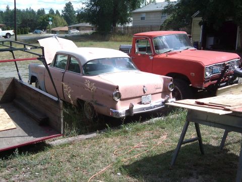 1988 Ford Bronco - A pink 1955 sedan with a white roof is parked next to a red truck, with its hood open.
