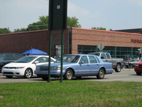 1988 Mercury Grand Marquis - A blue sedan is parked on the side of the road with other vehicles nearby.