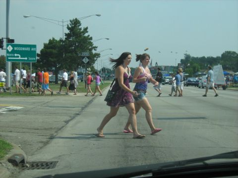 1988 Mercury Grand Marquis - A Woodward Avenue sign is visible as two women cross the street during a sunny day event.