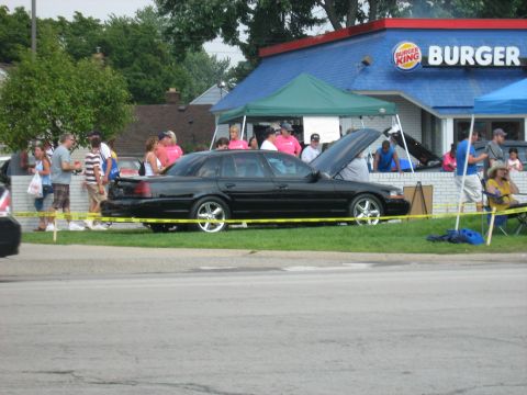 1988 Mercury Grand Marquis - Black sedan parked outside a Burger King with its hood up, attended by a small crowd.
