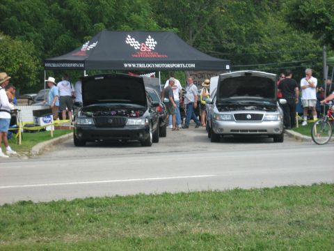 1988 Mercury Grand Marquis - Two Mercury Grand Marquis sedans are parked under a tent with their hoods open.
