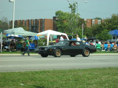 1988 Mercury Grand Marquis - A black 1977 Pontiac Firebird Trans Am cruises by onlookers at a car show.