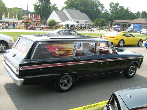 1988 Mercury Grand Marquis - A black station wagon with a custom Road Runner decal on the rear window is parked at an outdoor event.