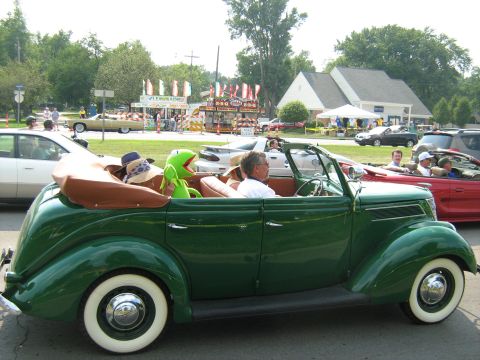 1988 Mercury Grand Marquis - A vintage green convertible, possibly from 1936, is seen with Kermit the Frog and passengers at an outdoor event.