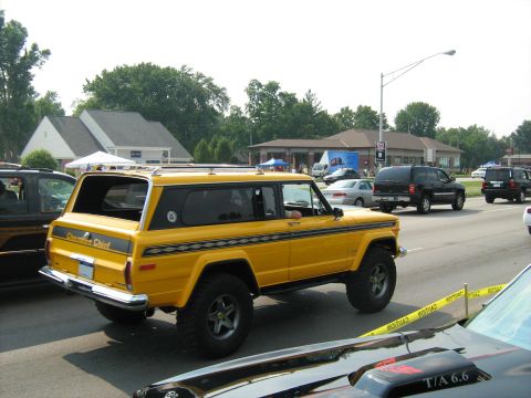 1988 Mercury Grand Marquis - Yellow Jeep Cherokee Chief SUV seen on the road with other vehicles present.