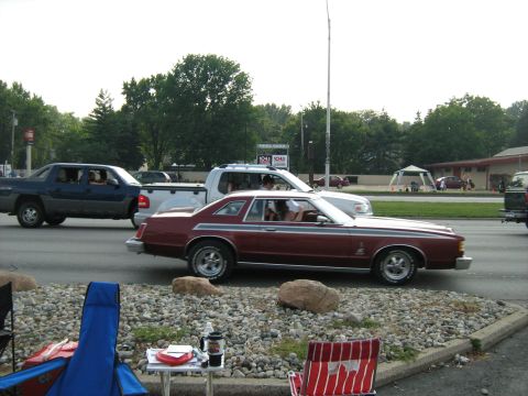 1988 Mercury Grand Marquis - A maroon coupe with woodgrain trim is seen driving on a road with other vehicles.