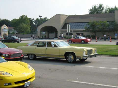 1988 Mercury Grand Marquis - A yellow 1977 Mercury Grand Marquis sedan is seen on the street with other vehicles around.