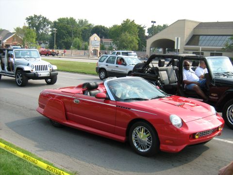 1988 Mercury Grand Marquis - A red convertible is seen driving in a parade with other vehicles.
