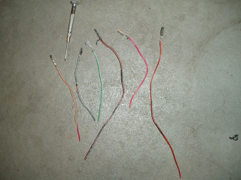 Six wire pigtails with crimp terminals and a small screwdriver on a concrete floor