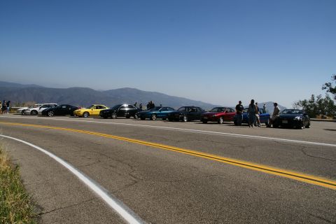 1993 Ford Taurus - A group of cars are parked on the shoulder of a scenic mountain road.