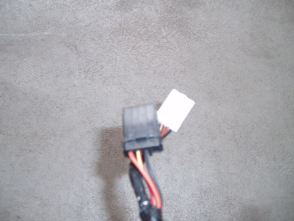 Black multi-pin automotive wiring harness connector with white label on gray carpet