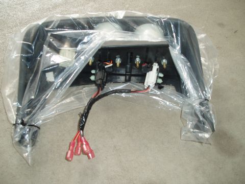 2003 Ford Crown Victoria - Back side of a black plastic dash bezel or overhead console assembly resting in a clear plastic bag on carpet. Two white bulb housings, fou…