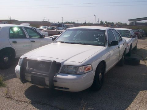 2003 Ford Crown Victoria - This white Ford Crown Victoria, marked as Lot 3, is parked in an outdoor lot with other vehicles.