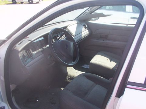 2003 Ford Crown Victoria - The interior of a 2003 Ford Crown Victoria appears worn, with visible dust and debris on the floor.