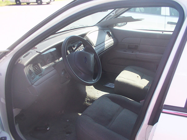 Gray Ford sedan interior with black cloth seats seen through the open driver's door