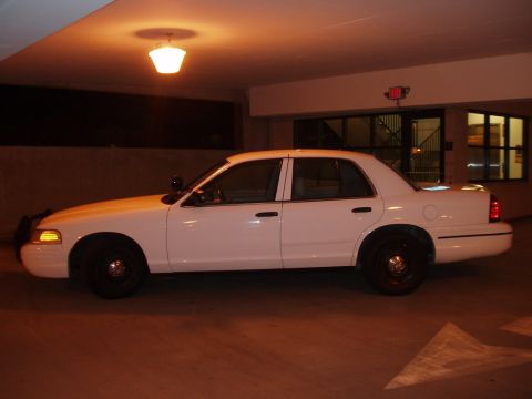 2003 Ford Crown Victoria - Side profile of a white 2003 Ford Crown Victoria sedan parked under an overhang.