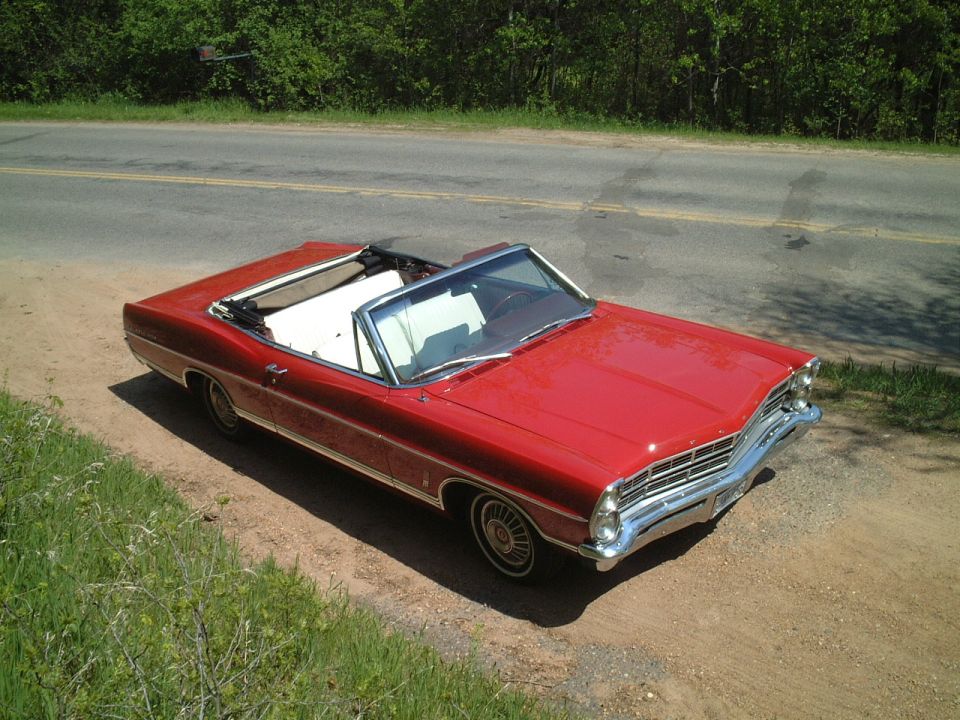 Red 1967 Ford Galaxie convertible, top down, parked on dirt roadside