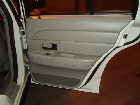 2003 Ford Crown Victoria - Interior view of a car's rear door panel, showing gray upholstery and a black door handle.