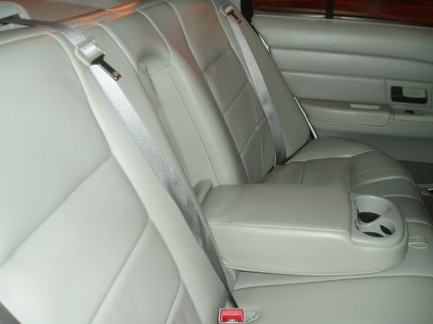 2003 Ford Crown Victoria - The interior of a car shows the back seat with seatbelts and a fold-down armrest.