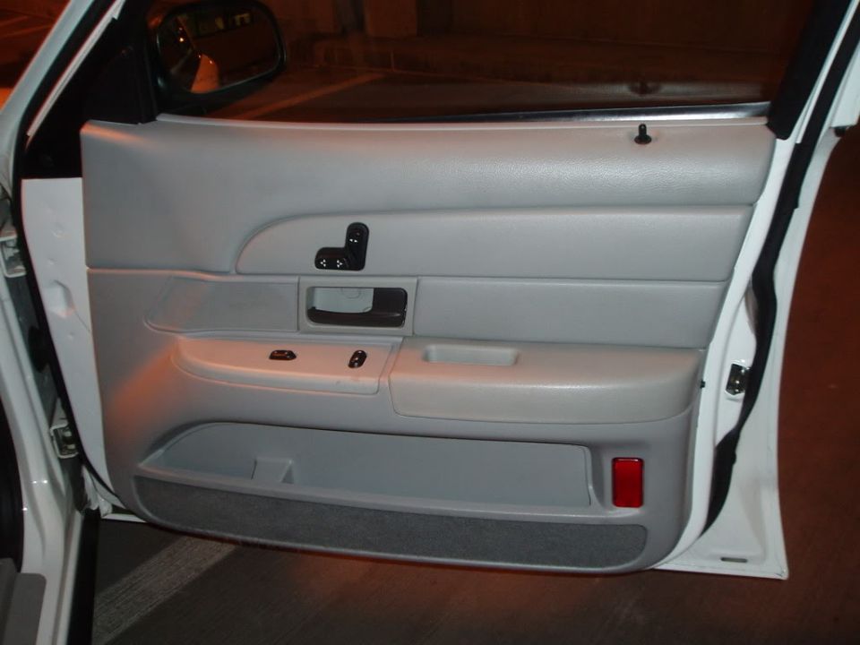 Gray car door panel with window controls and a red reflector