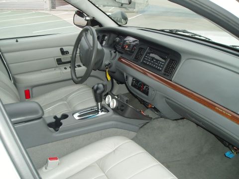 2003 Ford Crown Victoria - The interior of a 2003 Ford Crown Victoria features gray leather seats and a wood-grain trim on the dashboard.